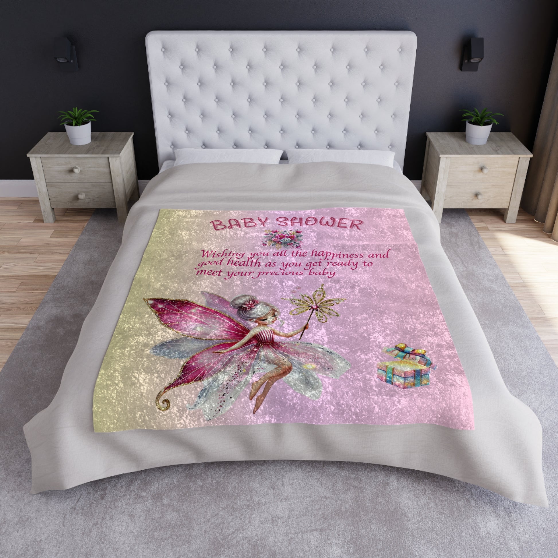 Bedspread with fairy design and baby shower text on a bed in a bedroom setting.